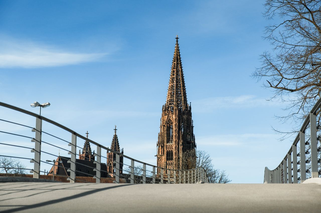 View of the iconic Münster Cathedral Tower from a bridge on a clear spring day.